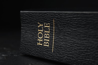 Photo of Hardcover Holy Bible in English language on black table, closeup