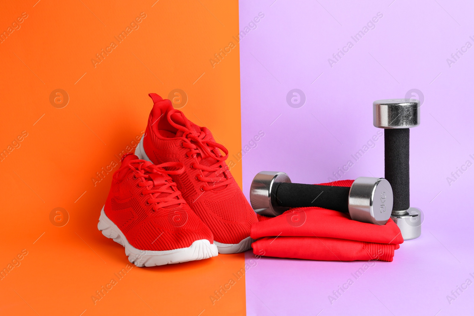 Photo of Pair of stylish red sneakers and dumbbells on color background