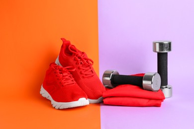 Photo of Pair of stylish red sneakers and dumbbells on color background