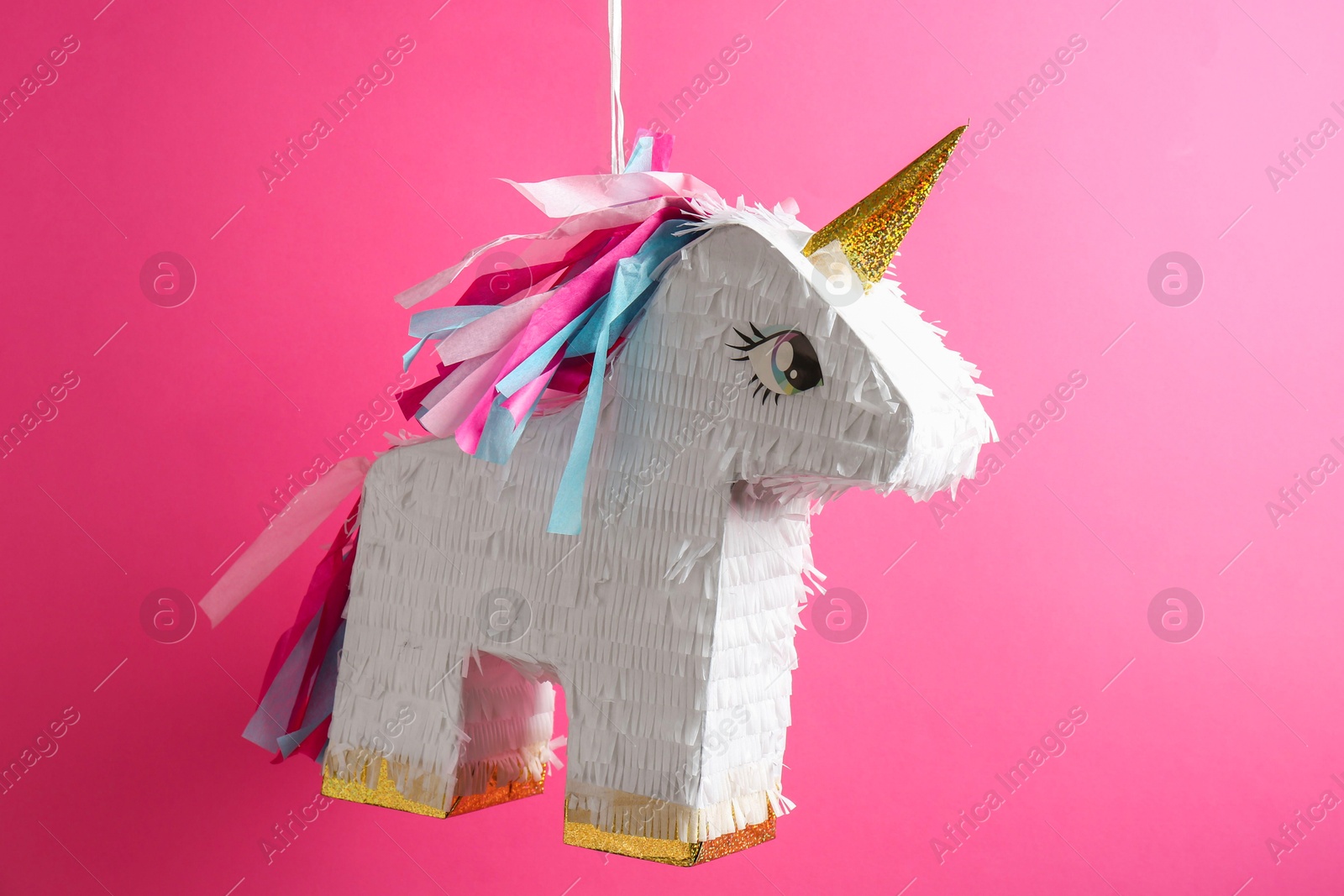 Photo of Bright pinata in shape of unicorn hanging on pink background