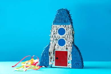 Photo of Bright pinata in shape of spaceship on blue background