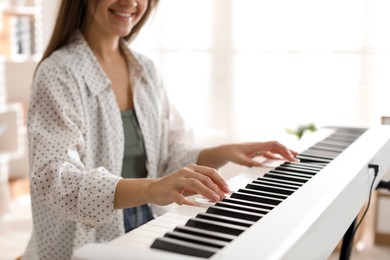 Woman playing synthesizer indoors, closeup. Electronic musical instrument