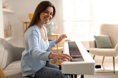 Smiling woman playing synthesizer at home. Electronic musical instrument