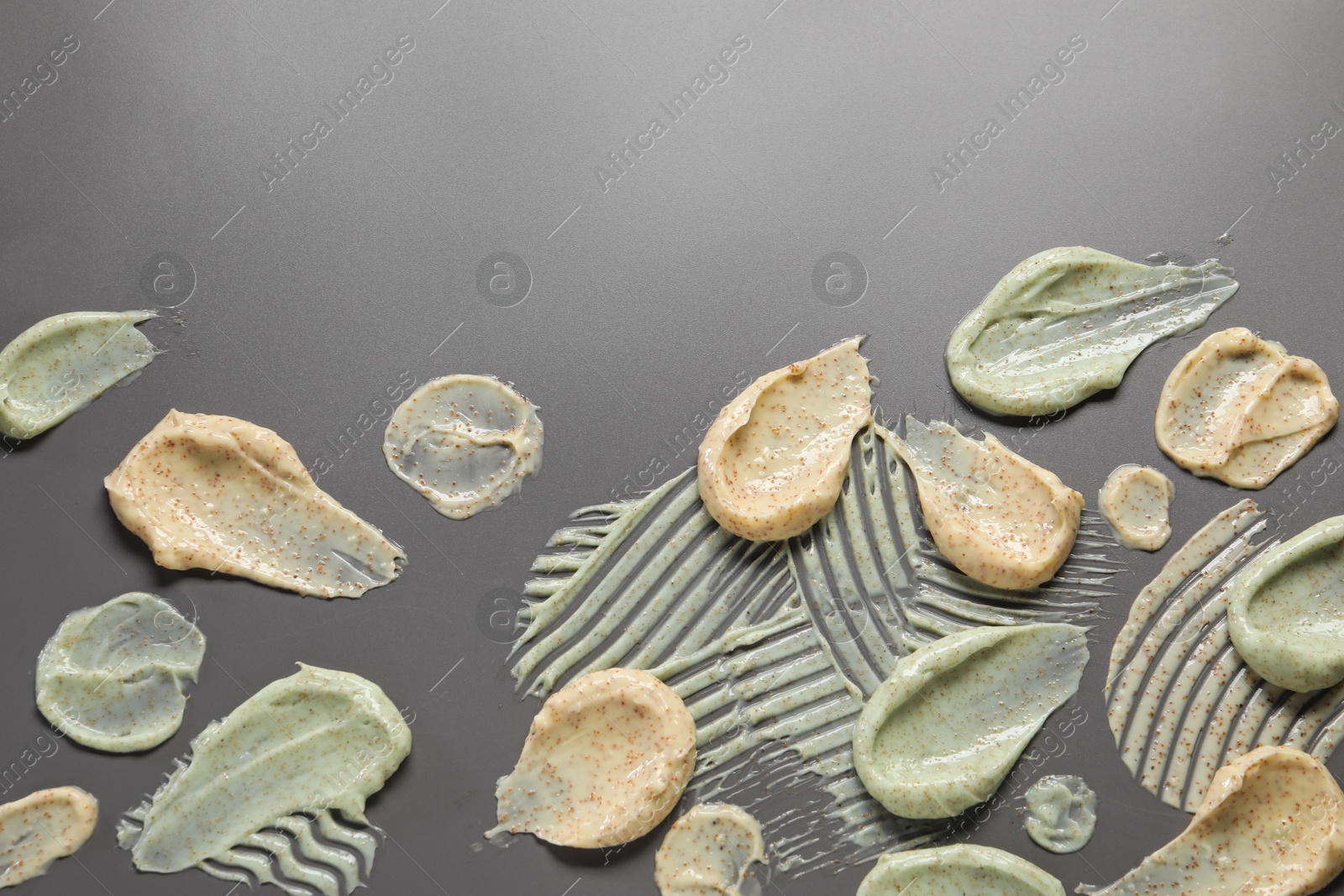 Photo of Samples of body scrubs on grey background, flat lay. Space for text