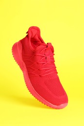 Photo of Stylish red sneaker in air against yellow background