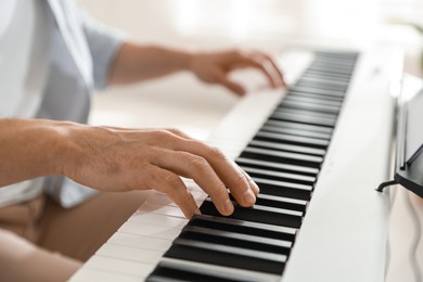 Photo of Man playing synthesizer indoors, closeup. Electronic musical instrument