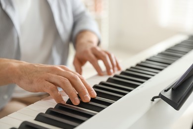 Photo of Man playing synthesizer indoors, closeup. Electronic musical instrument