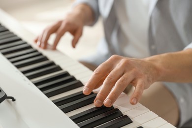 Photo of Man playing synthesizer indoors, closeup. Electronic musical instrument