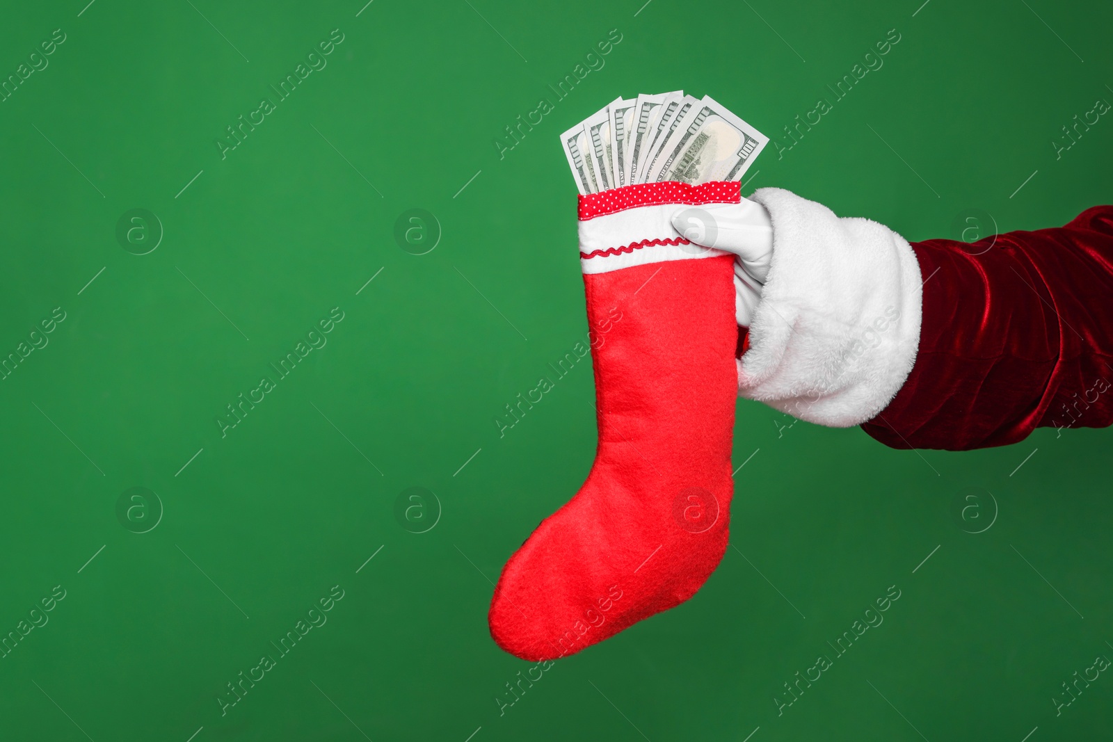 Photo of Santa Claus holding stocking with dollar banknotes on green background, closeup. Space for text