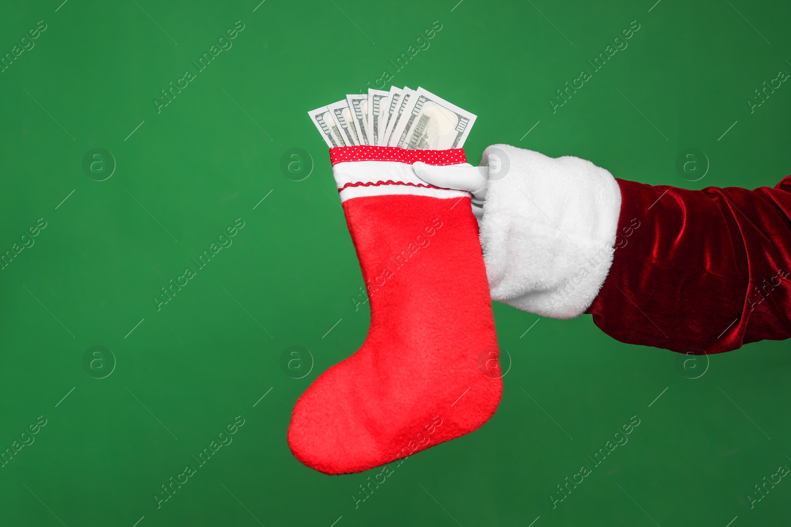 Photo of Santa Claus holding stocking with dollar banknotes on green background, closeup. Space for text