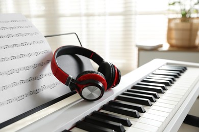 Photo of Synthesizer with music sheet and headphones indoors, closeup