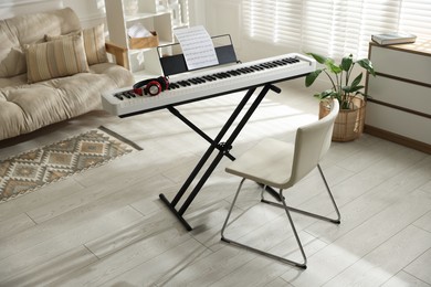 Photo of Synthesizer with music sheet, headphones and chair indoors