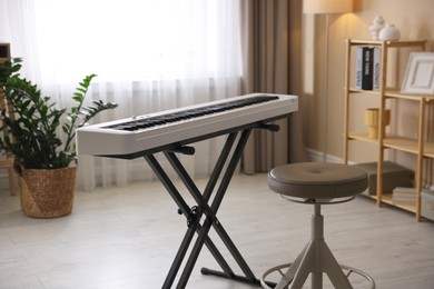 Photo of Synthesizer and stool indoors. Electronic musical instrument