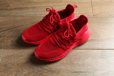 Photo of Pair of stylish red sneakers on wooden background