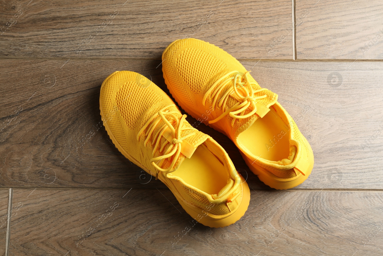 Photo of Pair of stylish yellow sneakers on wooden background, top view