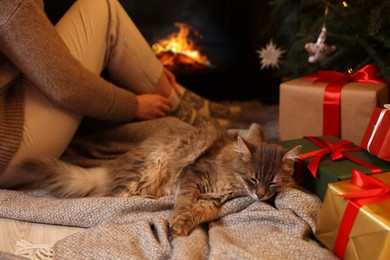 Photo of Woman and cute fluffy cat in room decorated for Christmas, closeup