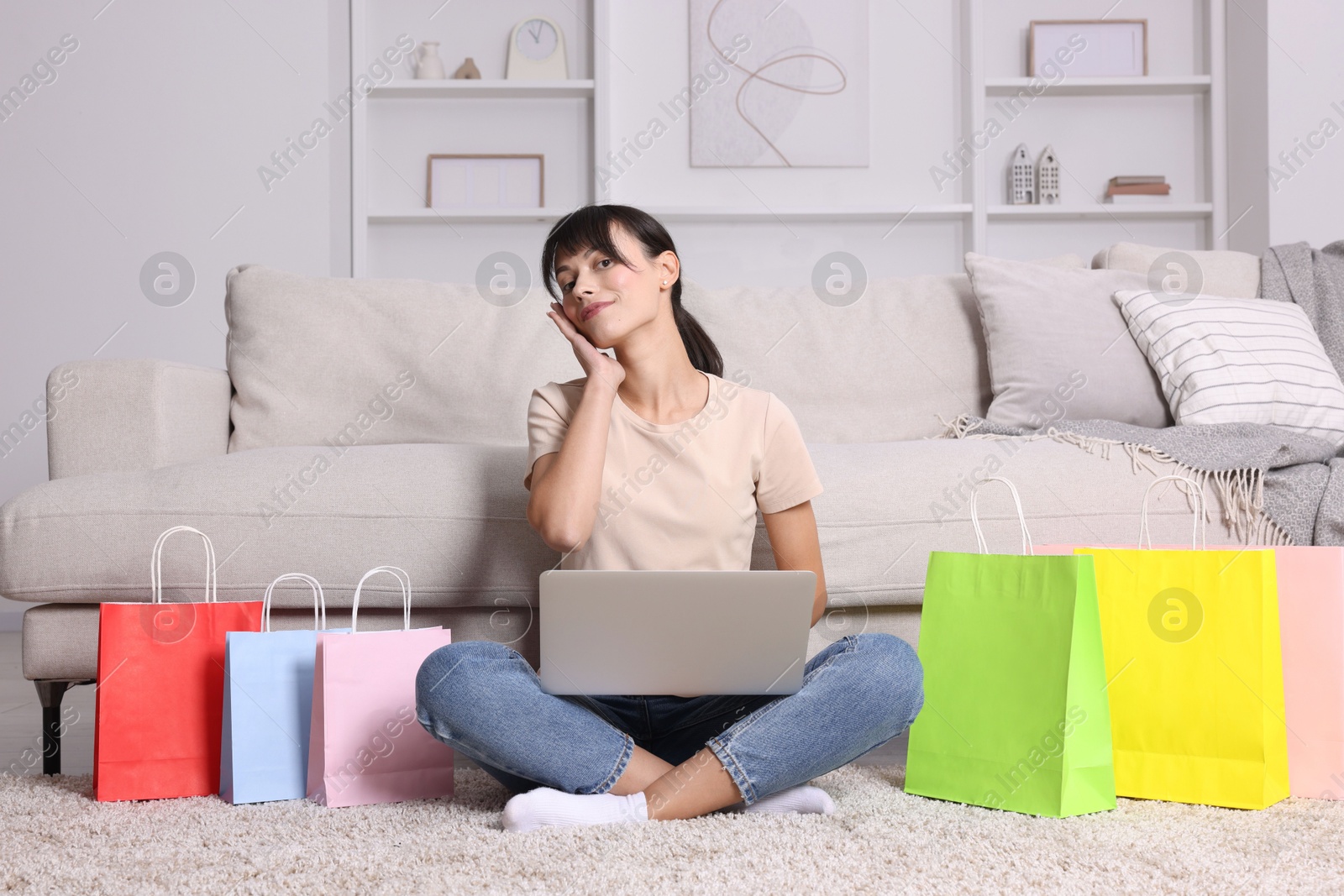 Photo of Internet shopping. Beautiful woman with laptop and colorful bags at home