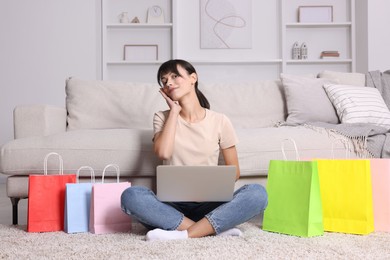 Internet shopping. Beautiful woman with laptop and colorful bags at home