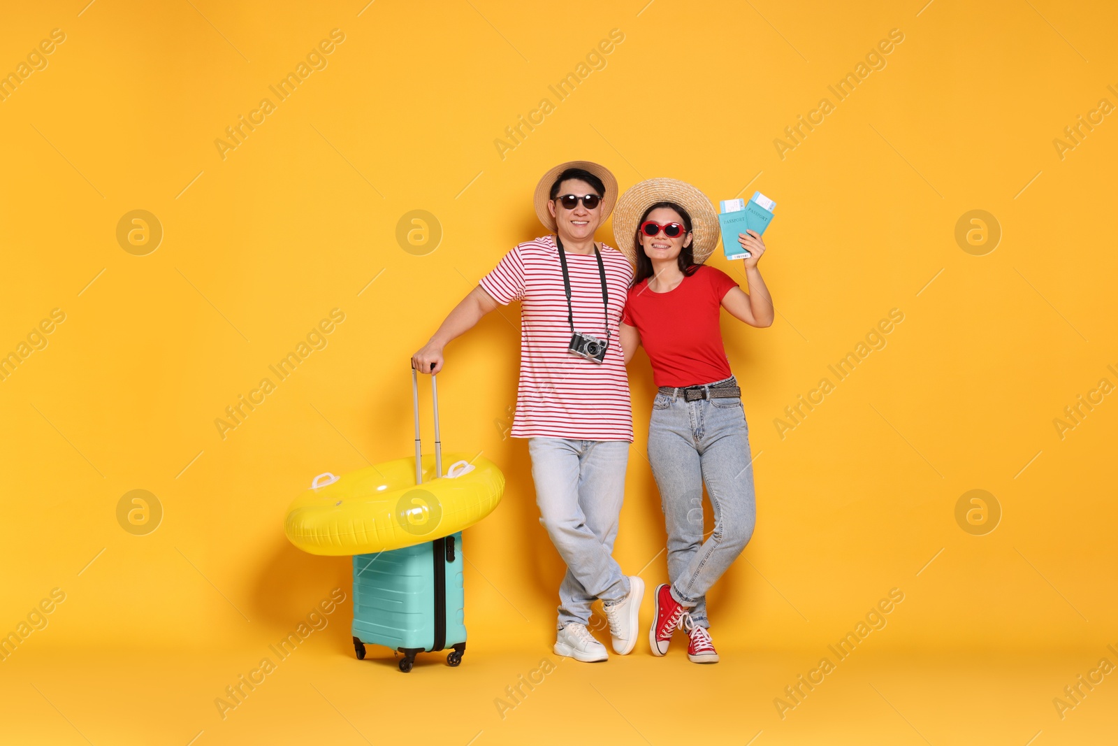 Photo of Travellers with passports, inflatable ring and suitcase on yellow background