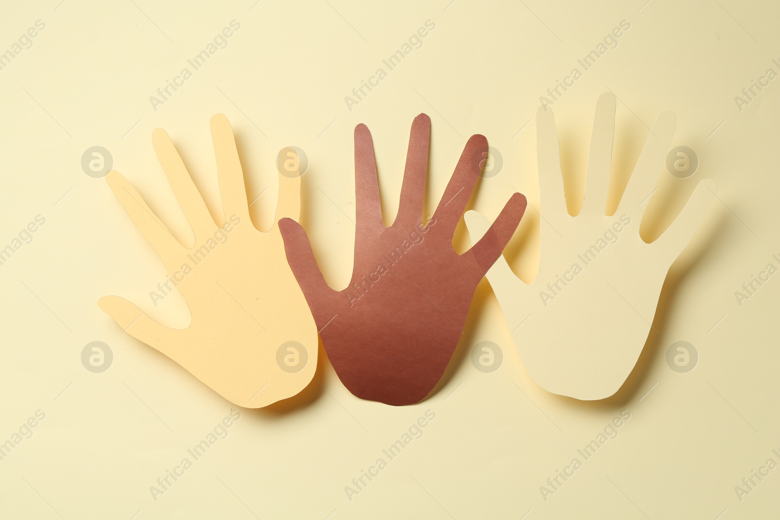 Photo of Stop racism. Paper palms of different colors on beige background, top view