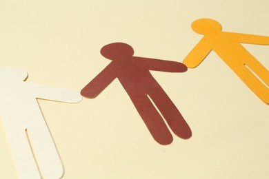 Photo of Stop racism. Paper human figures of different colors on beige background, closeup