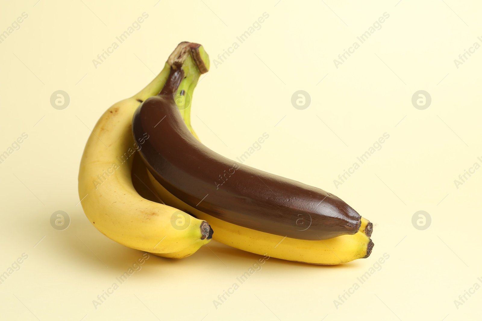 Photo of Stop racism. Bunch of yellow bananas with dark one on beige background, space for text