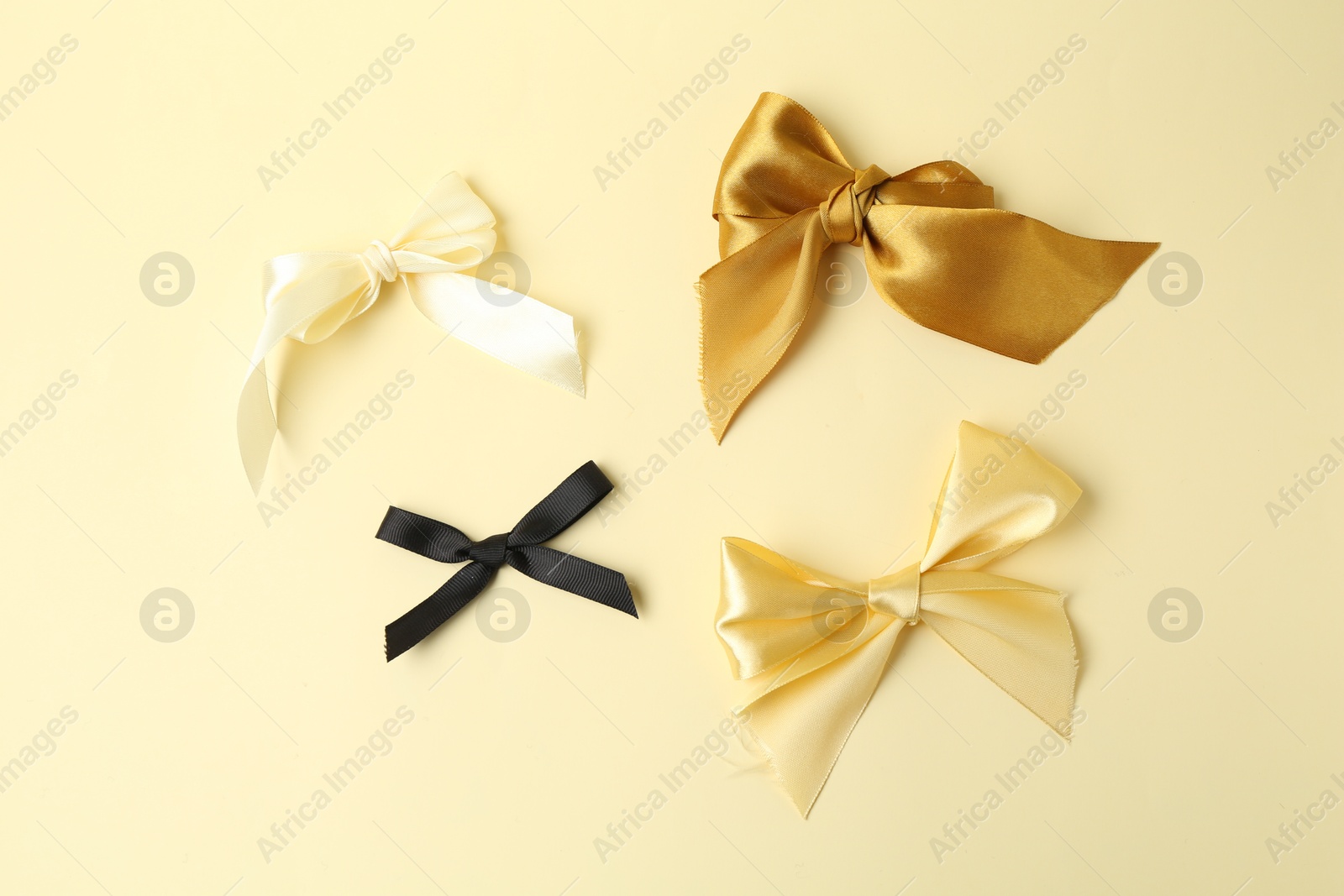 Photo of Beautiful bows of different colors on beige background, flat lay. Racism concept