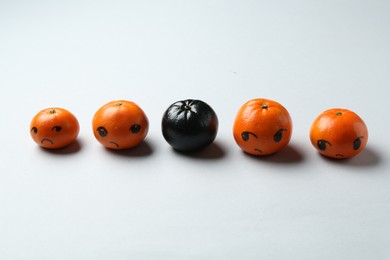 Photo of Stop racism. One black tangerine among orange ones on light background