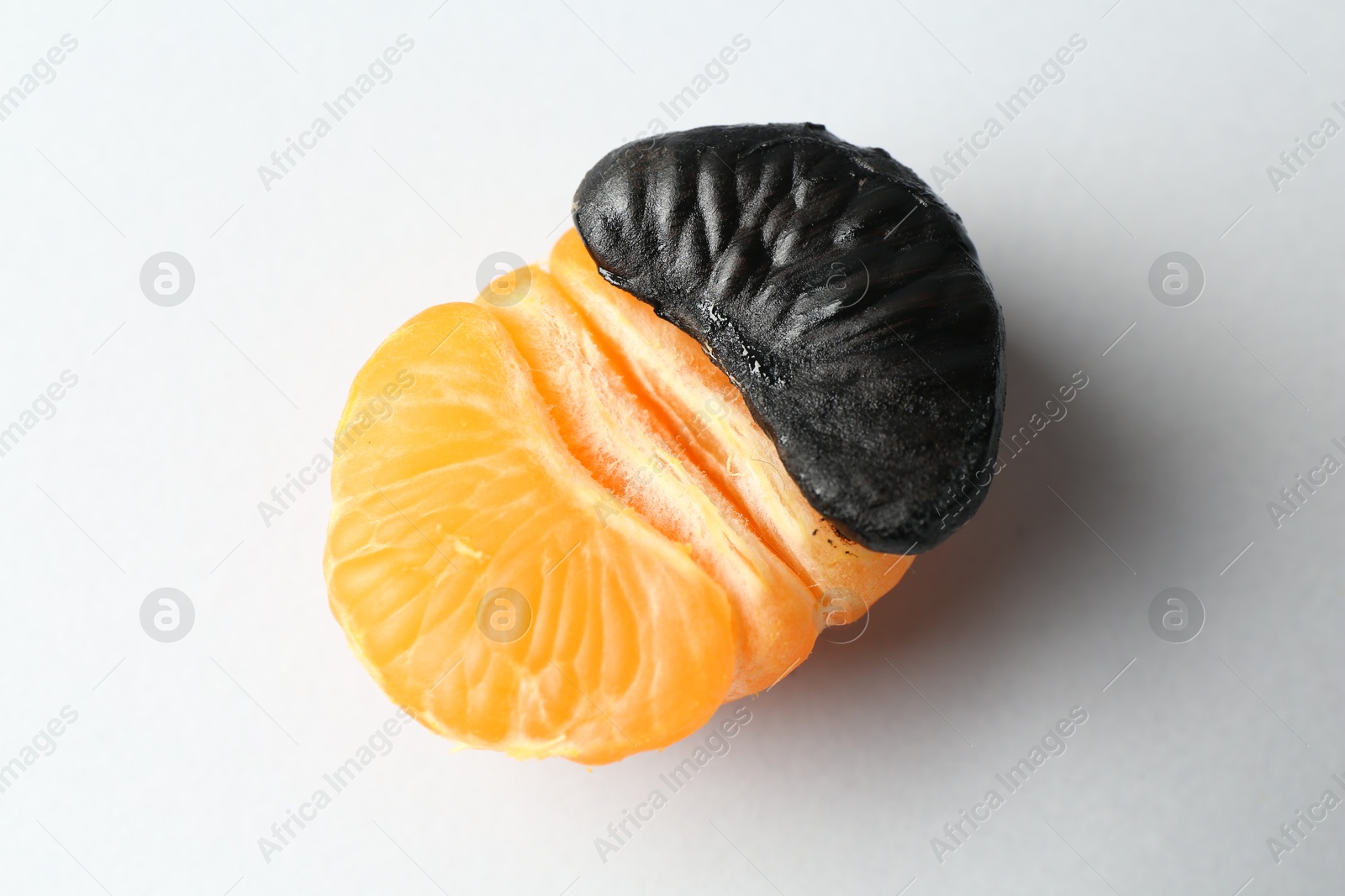 Photo of Stop racism. Half of tangerine with black piece on light background, closeup