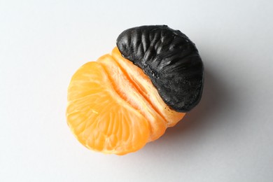 Photo of Stop racism. Half of tangerine with black piece on light background, closeup