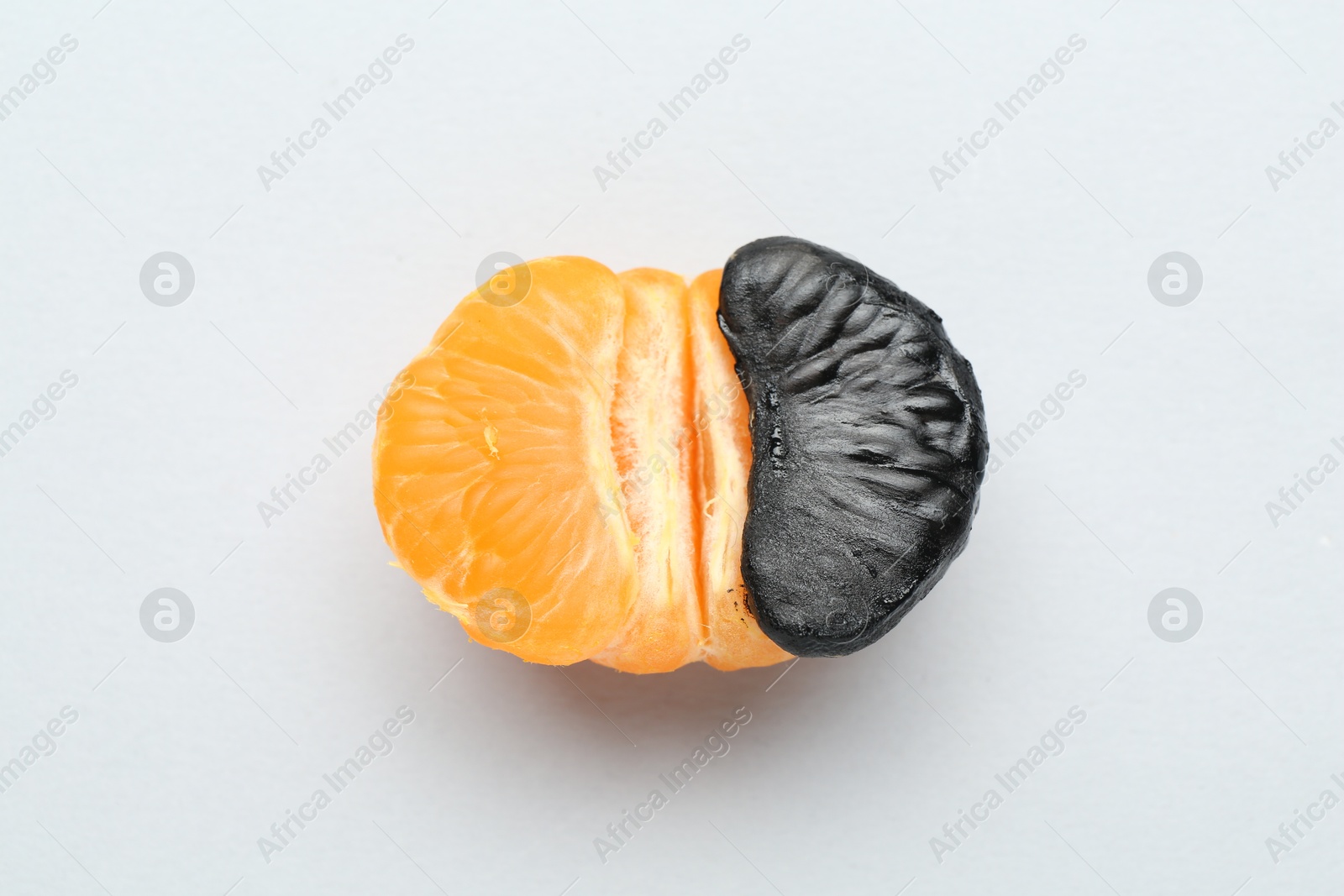 Photo of Stop racism. Half of tangerine with black piece on light background, top view