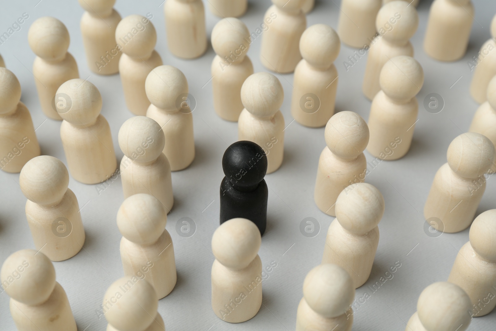 Photo of Stop racism. Black human figure among white ones on light background