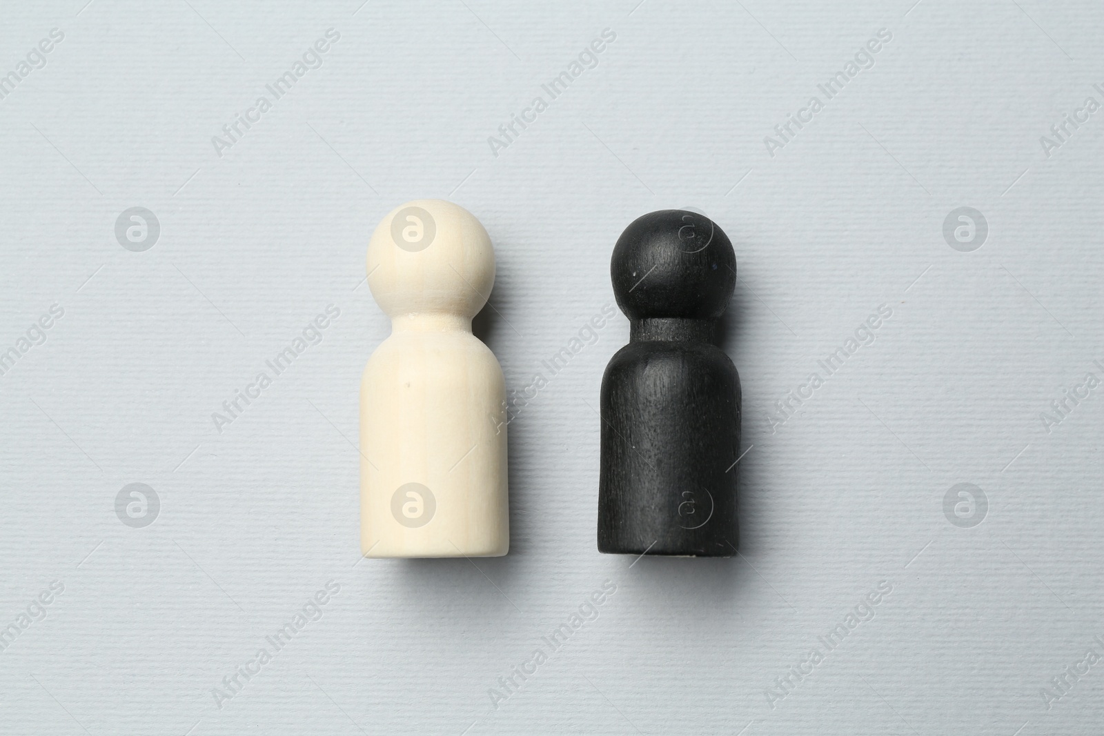 Photo of Black and white human figures on light background, flat lay. Racism concept