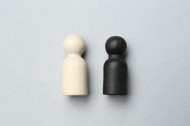 Photo of Black and white human figures on light background, flat lay. Racism concept