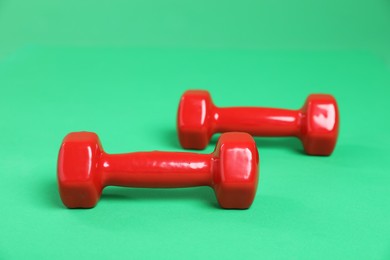 Photo of Red dumbbells on green background. Sports equipment