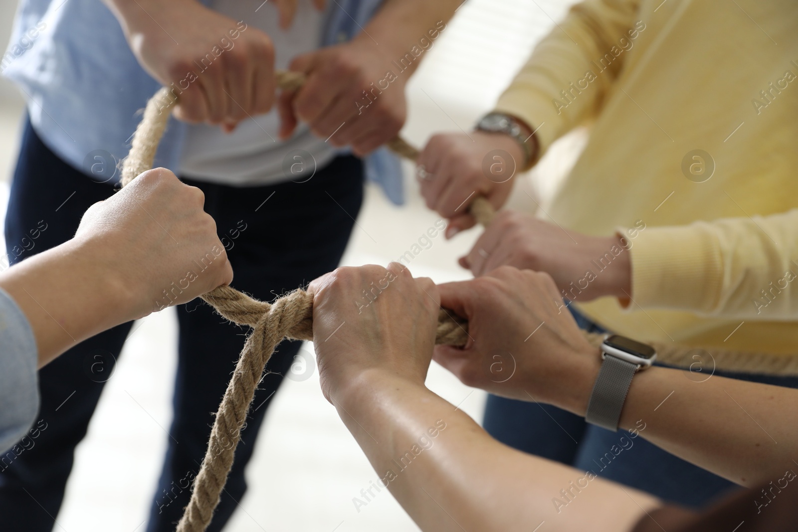 Photo of Unity concept. People holding rope together indoors, closeup