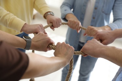 Photo of Unity concept. People holding rope together indoors, closeup