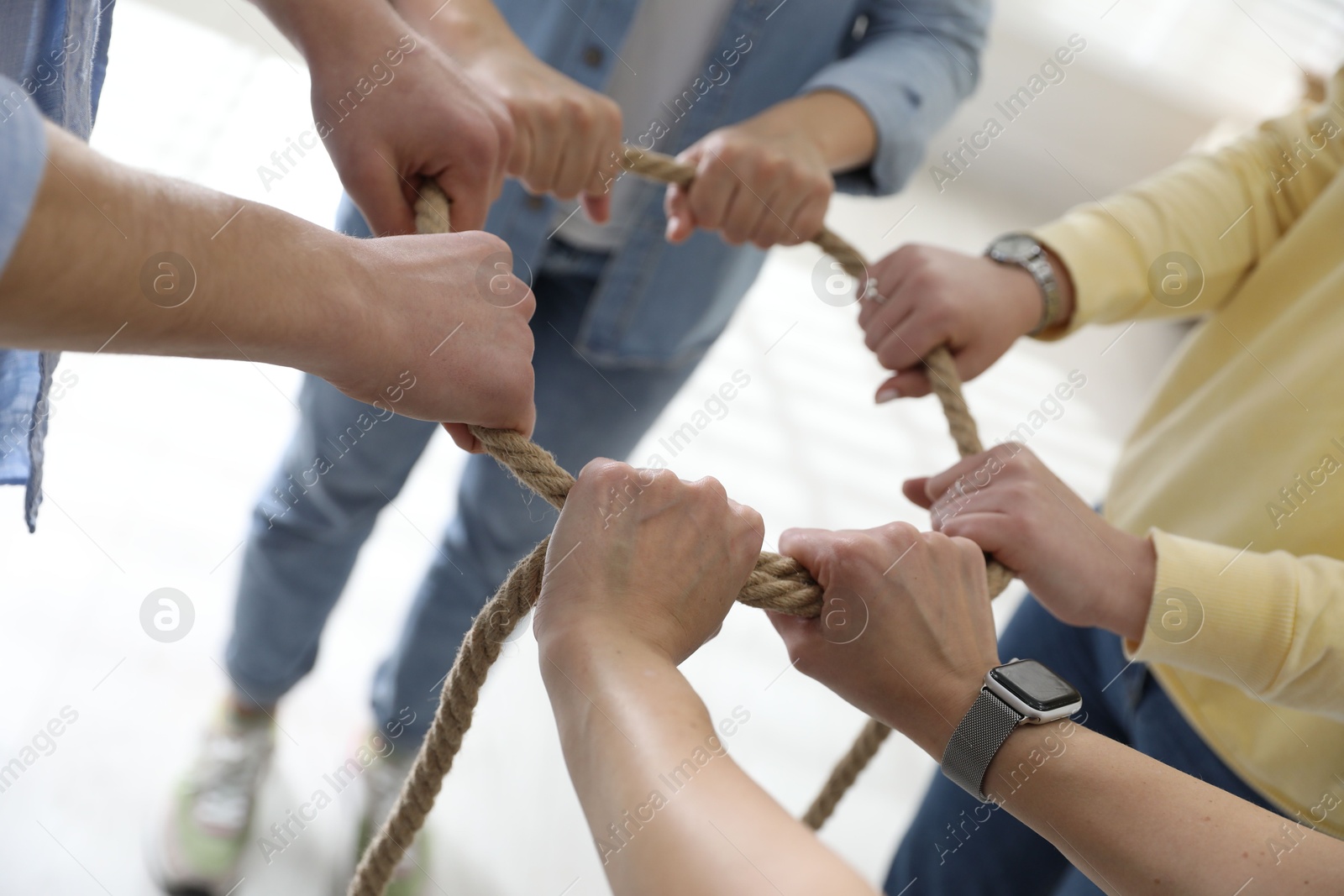 Photo of Unity concept. People holding rope together indoors, closeup