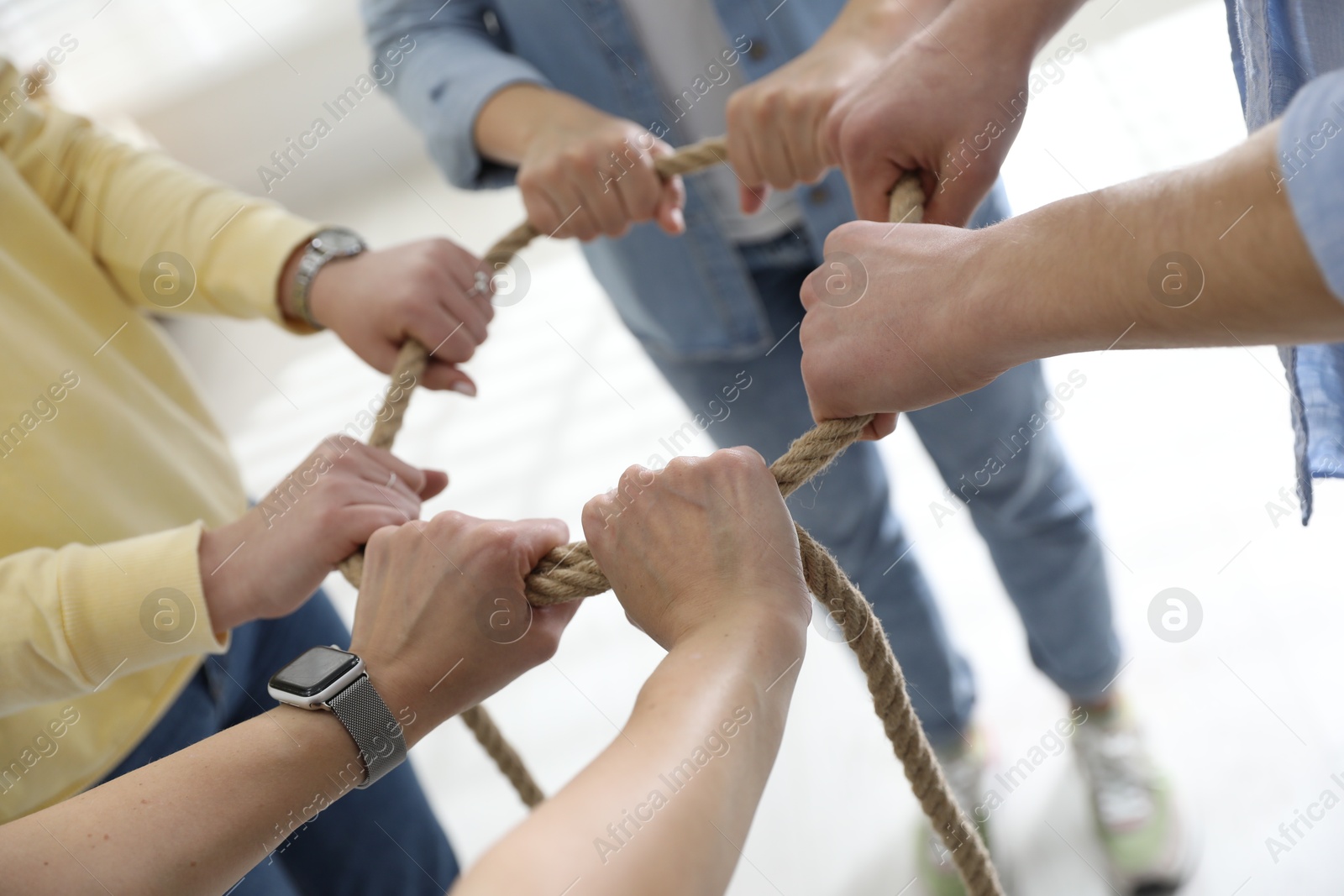 Photo of Unity concept. People holding rope together indoors, closeup