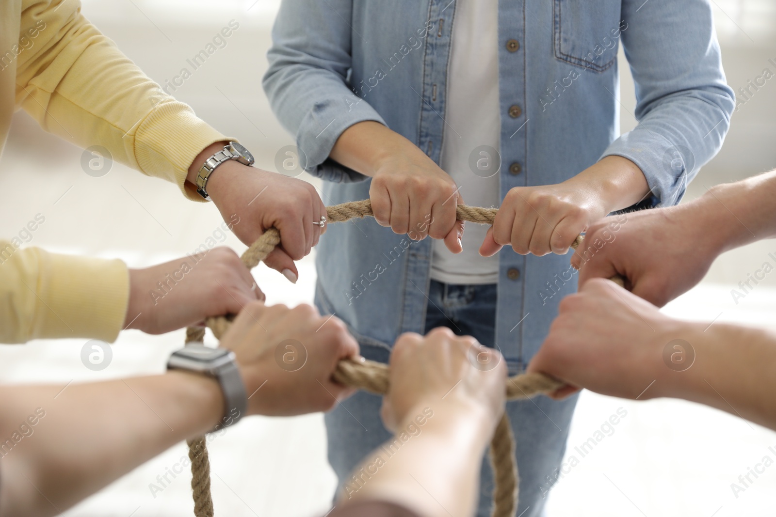 Photo of Unity concept. People holding rope together indoors, closeup