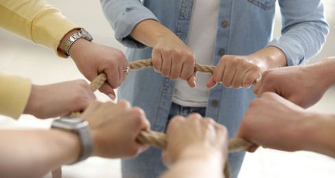 Photo of Unity concept. People holding rope together indoors, closeup