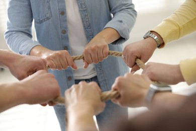 Photo of Unity concept. People holding rope together indoors, closeup