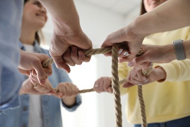 Photo of Unity concept. People holding rope together indoors, closeup