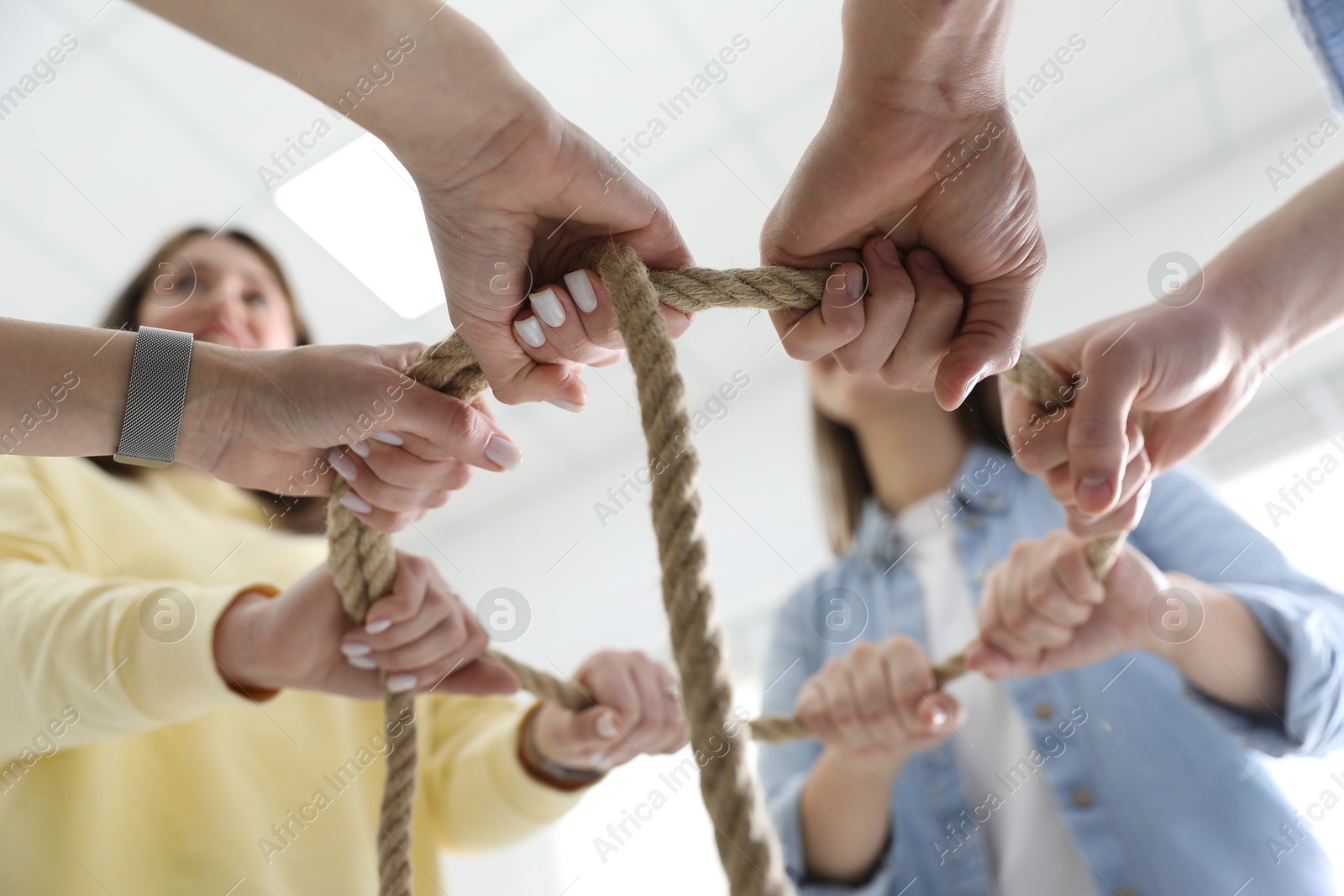 Photo of Unity concept. People holding rope together indoors, bottom view