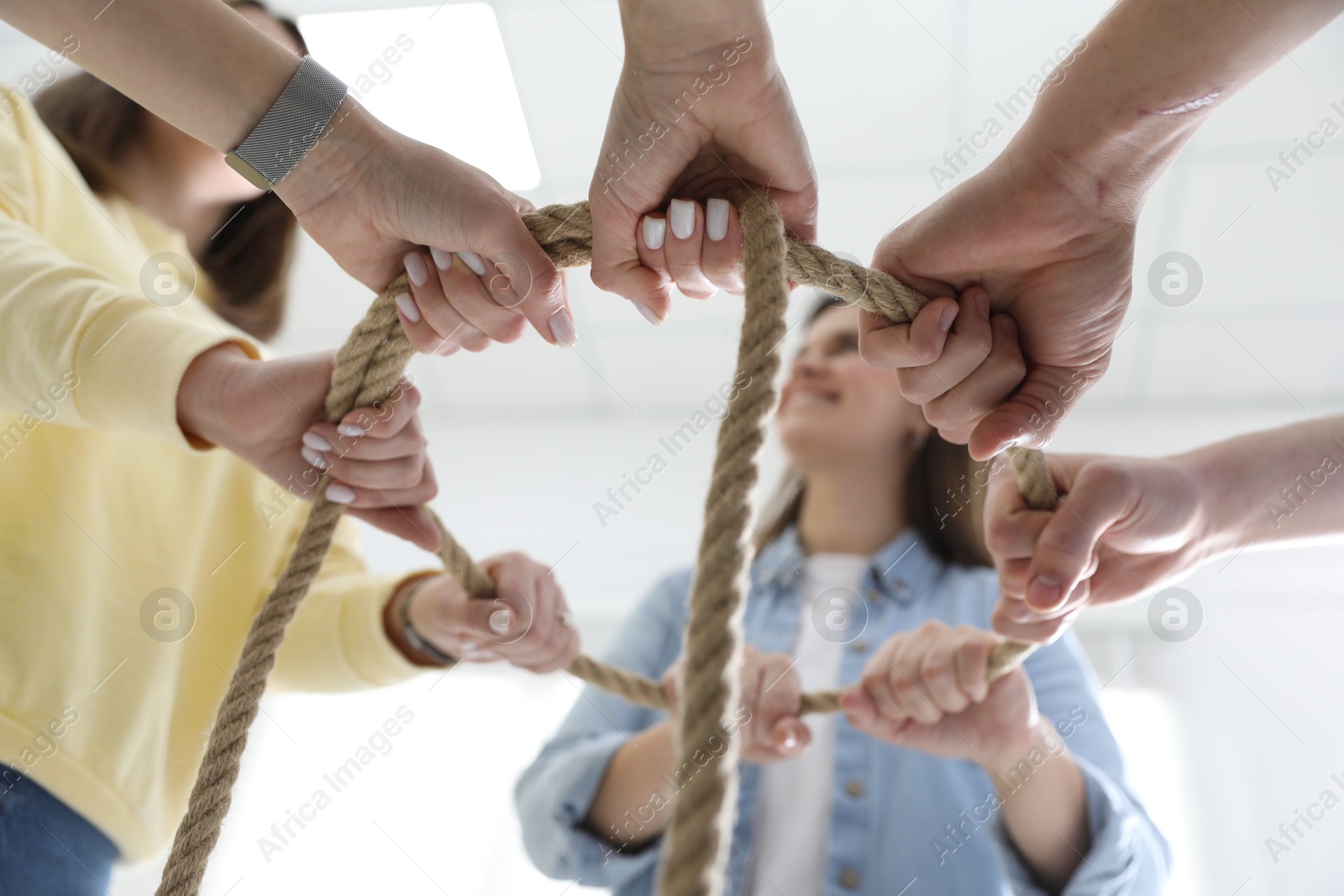 Photo of Unity concept. People holding rope together indoors, bottom view