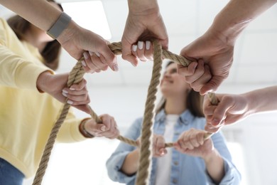 Unity concept. People holding rope together indoors, bottom view