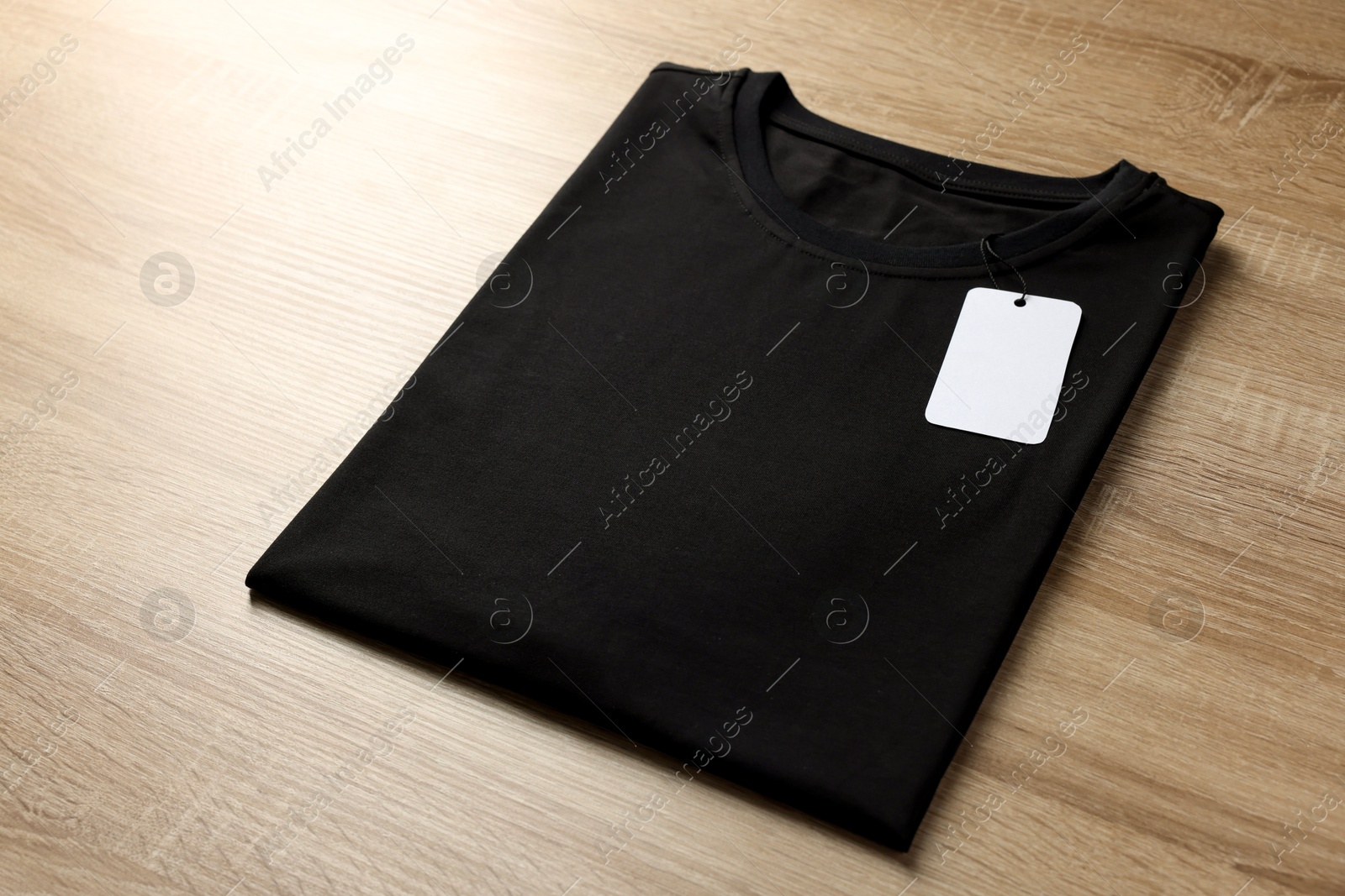 Photo of One blank t-shirt on wooden background, closeup. Mockup for design