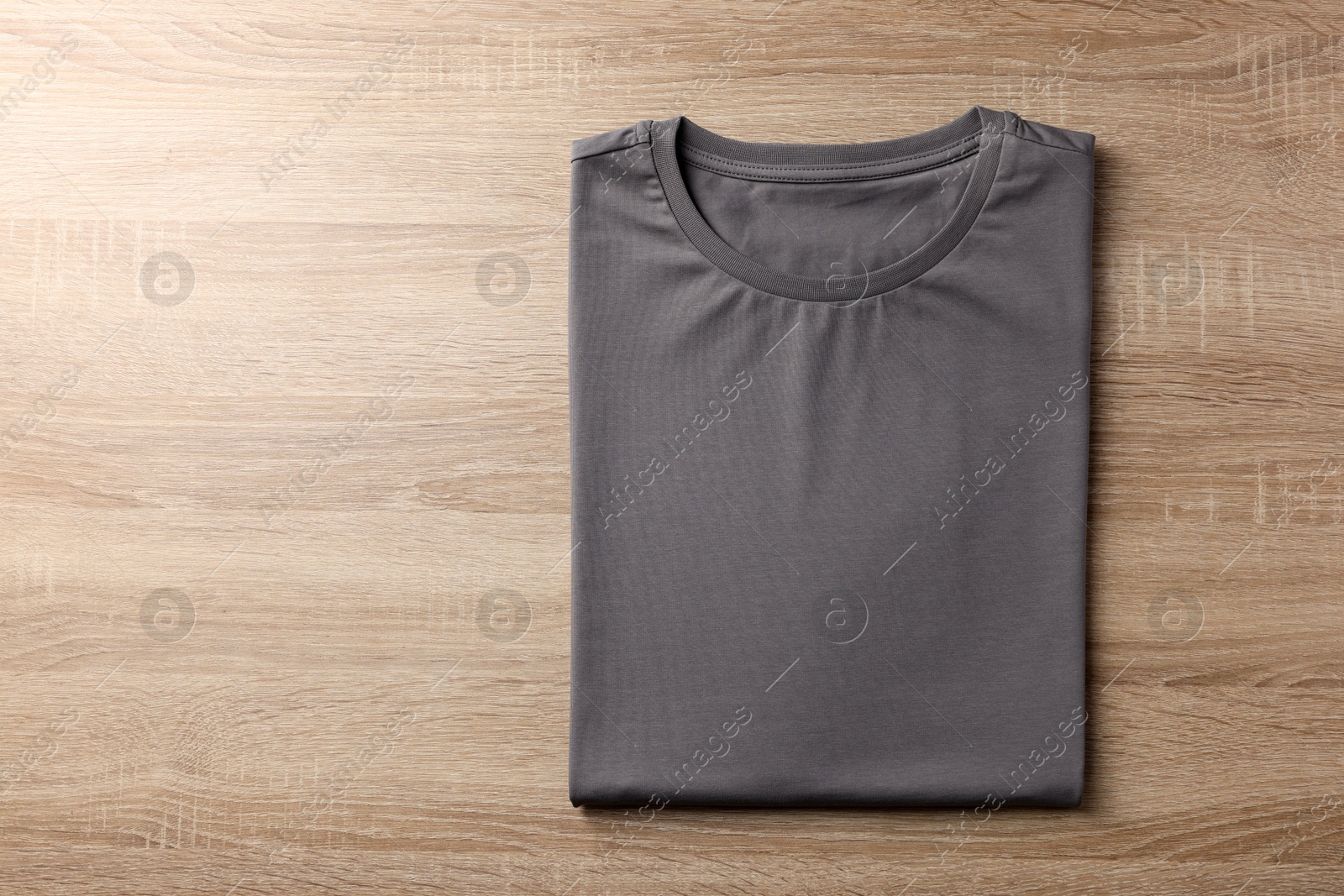 Photo of One blank t-shirt on wooden background, top view. Mockup for design