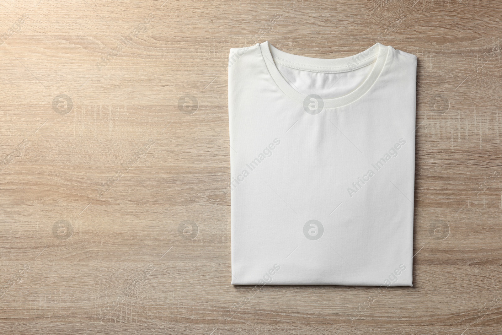 Photo of One blank t-shirt on wooden background, top view. Mockup for design