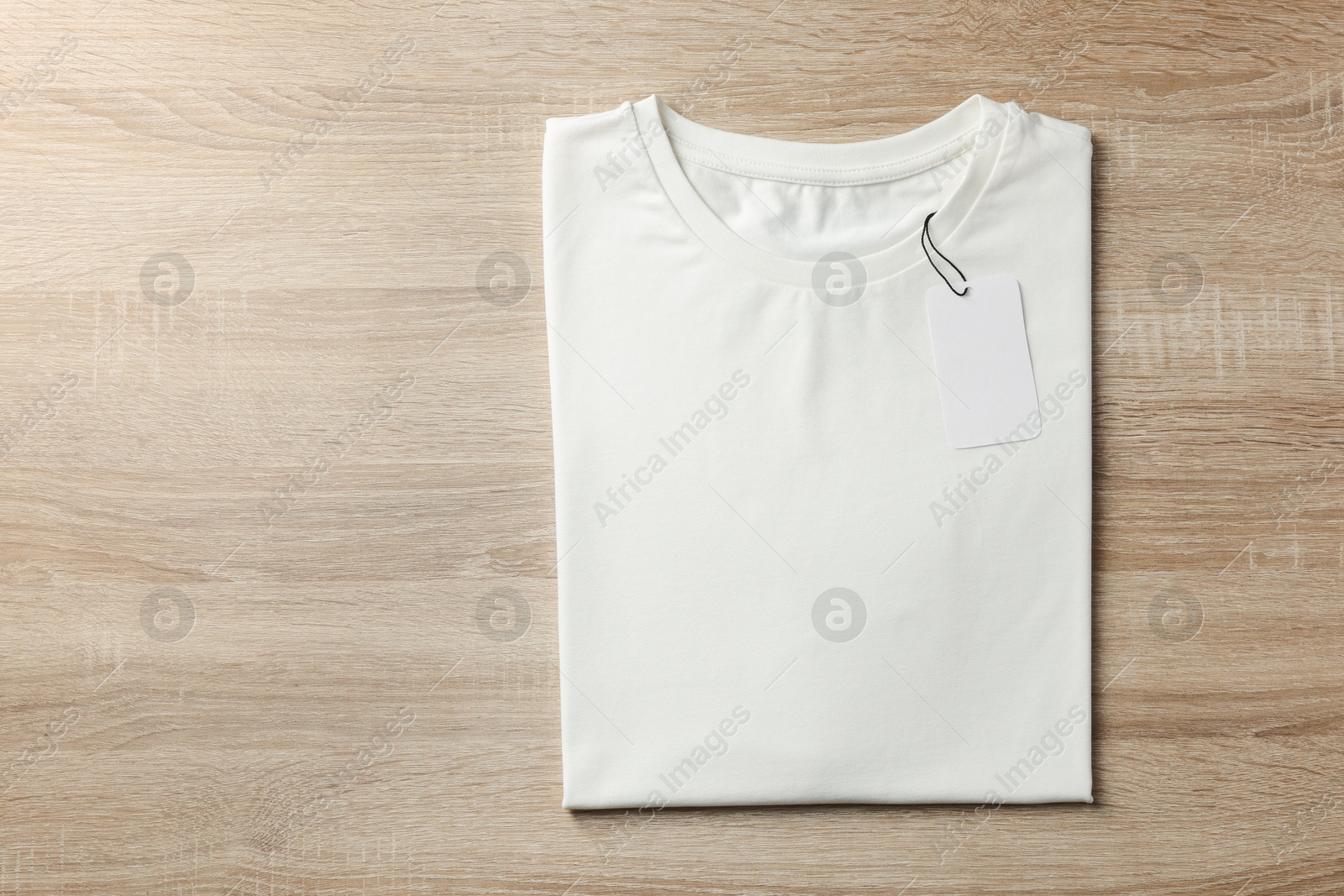 Photo of One blank t-shirt on wooden background, top view. Mockup for design